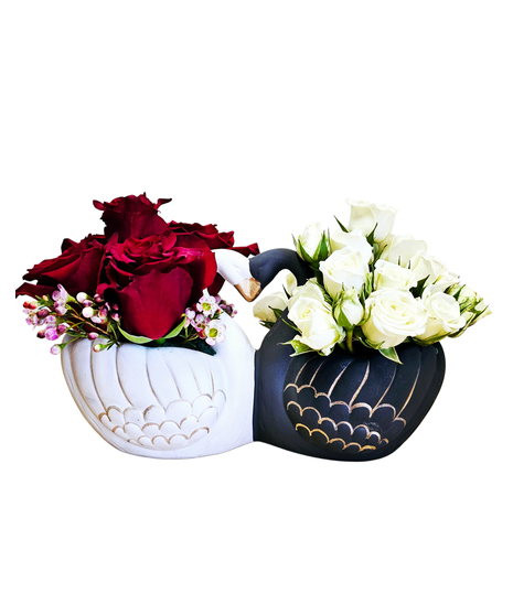 A ceramic container with a black and a white swan featuring red roses and white spray roses